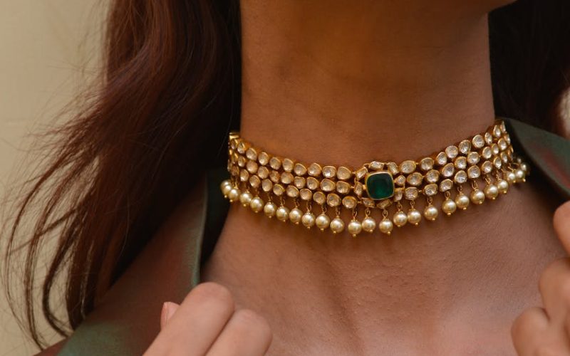 Close-up of a woman wearing a stylish gold and emerald jewelry set.